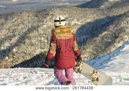 Snowboarder Girl Freerider Is Standing In The Snowy Mountains In Winter Under The Clouds