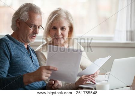 Happy Older Aged Couple Holding Reading Good News In Document