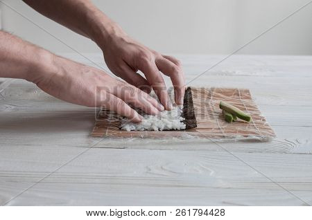 Process of making maki sushi. Cook chef hands preparing rolls with cheese, avocado and sesame seeds 