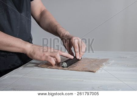 Process of making maki sushi. Cook chef hands preparing rolls with cheese, avocado and sesame seeds 