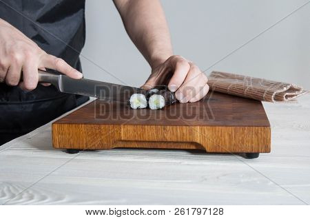Process of making maki sushi. Cook chef hands preparing rolls with cheese, avocado and sesame seeds 