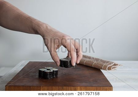 Process of making maki sushi. Cook chef hands preparing rolls with cheese, avocado and sesame seeds 