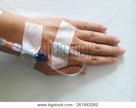 Patient Hand With The Tube Of Normal Saline Infusion On White Cloth Background