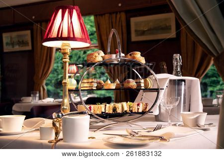 Vintage Late Afternoon Tea Stand With Sandwiches, Cakes And Tea As See Through The Window Of A Train