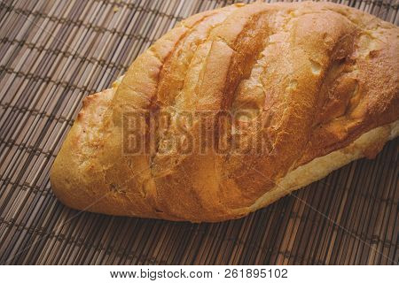 Bun On A Straw Brown Litter.
Freshly Baked Loaf Of Bread On A Straw Mat.