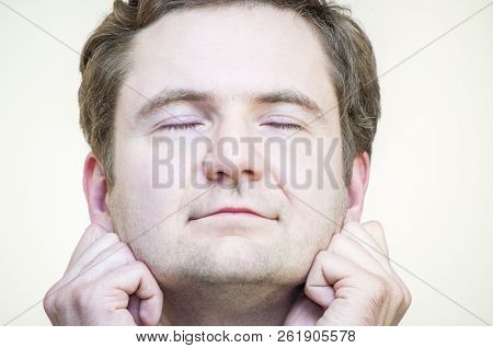 Portrait Of Young Caucasian Ethnicity Tranquil Meditating Man Holding His Earlobes On White Backgrou
