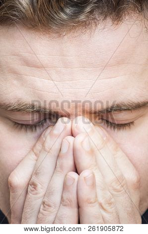 Portrait Of Young Tranquil Concentrated Man With Eyes Closed Covering Face With Palms On White Backg