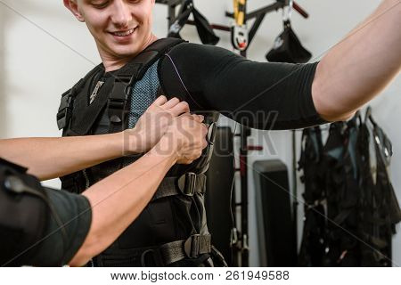 Woman Fastening Electro Muscular Stimulation Vest On Man
