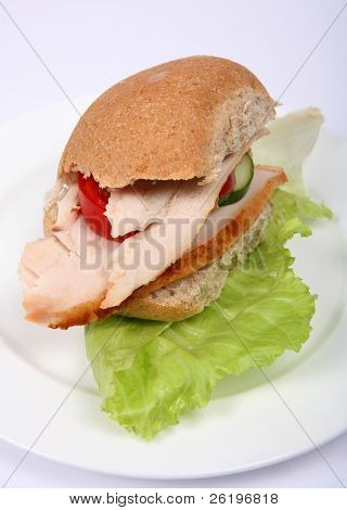 Brunt bröd rulle fylld med kallt kalkonbröst och sallad.