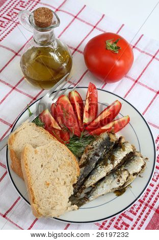 eine Mahlzeit von Sardinen, Brot und Tomaten, garniert mit Dill und Olivenöl.