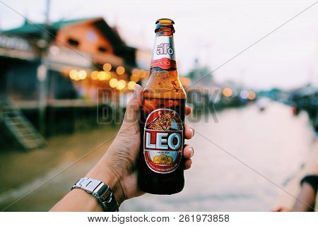 Bangkok0, Thailand - June 17 , 2018: Handed Bottle Of Cold Leo Beer On Dark Brown Bacony With Water 