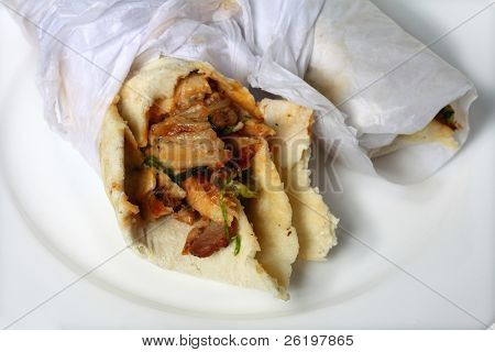 Dwie kanapki kurczak shawarma zawija się na białe płytki. Okłady są popularne sn na wynos fast-food