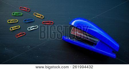 A Stepler And Colored Clips On Black Background