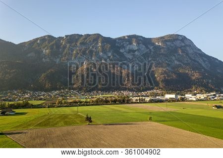 Aerial View Of Green Meadows With Villages And Forest In Austrian Alps Mountains.