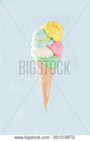 Stack Of Pastel Colorful Ice Cream Scoops In Waffle Cone, Isolated On Light Blue Background. Woman H