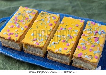 Four Tompouce Cakes With Whipped Cream And Yellow Icing Served In Sunny Spring Garden