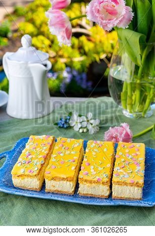 Four Tompouce Cakes With Whipped Cream And Yellow Icing Served In Sunny Spring Garden