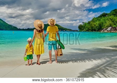 Family on beach, young couple in yellow with three year old boy. Summer vacation at Seychelles. Port Launay, Mahe. 