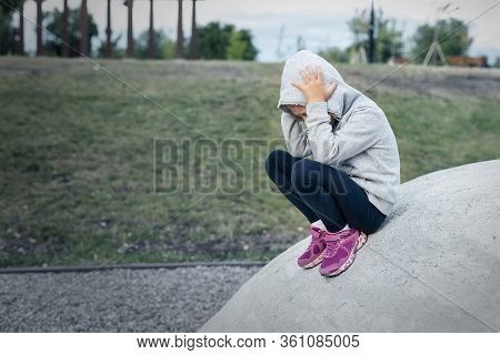 Upset Sad Depressed Little School Girl Sitting Alone At City Street Park Clutching Head. Upset Stres