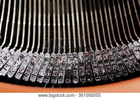 A Close-up Or A Macro Shot Of The Typebars Of A Retro-style Manual Typewriter Encased In A Hinged Re