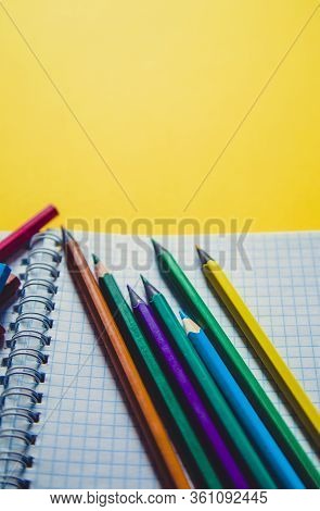 School Supplies On Yellow. Bright Back To School Background. Notepad And Stack Of Colorful Pencils. 