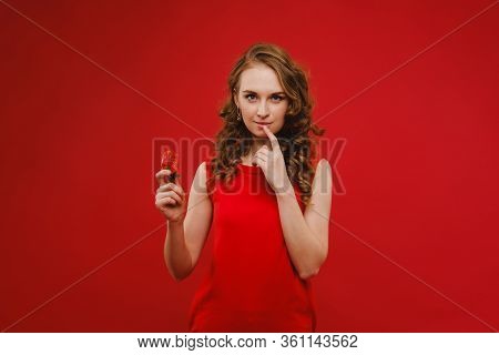A Beautiful Girl In A Red Dress On A Red Background Holds A Strawberry In Her Hands And Smiles