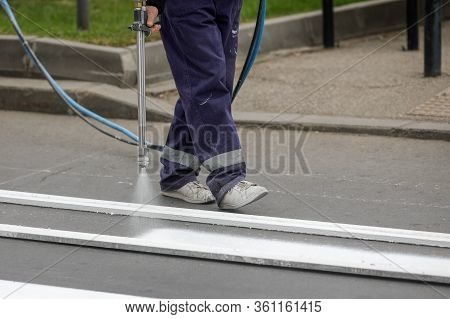 Details With A Road Worker Painting A Crosswalk On A City Street.
