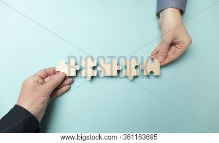 Two Hands Connect Puzzles On A Blue Background. Cooperation And Teamwork In Business. Collaboration 