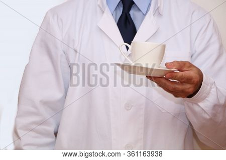 Close-up - A Doctor In A White Coat Holding A Cup Of Coffee In His Hand
