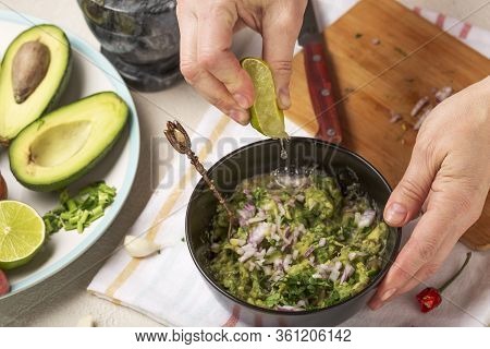 Process Of Preparation Of A Mexican Sauce Guacamole. Woman Squeeze Juice From Lime Fruit.