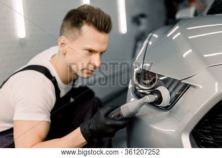 Detailing And Polishing Of Car Headlight On Car. Young Professional Concentrated Caucasian Male Work