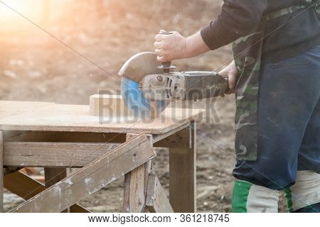Stonemason Cutting Brick With Diamond Saw Outdoors In A Cloud Of Dust