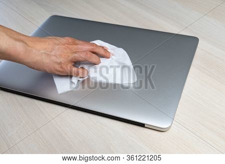 Laptop being wiped by a person to remove virus and to be protected from the virus during coronavirus pandemic