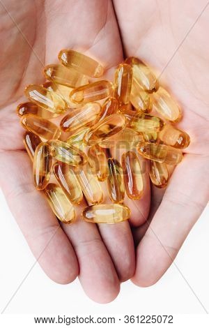 Close Up Of Hands With Gelcap Or Softgel Capsule Pills With Omega 3 And Vitamins D C As Medical Drug