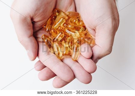 Close Up Of Hands Holding Gelcap Or Softgel Transparent Capsule Pills With Omega 3 And Vitamins C An