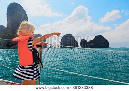 Happy Little Baby In Life Jacket On Board Of Sailing Boat Watching Offshore Sea And Tropical Islands