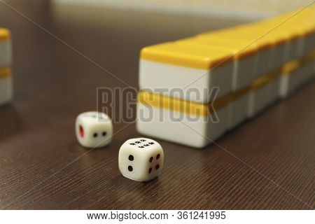 The Bones For The Mahjong Folded On Each Other And Two Playing Cubes Lie On The Brown Wood Table Tab
