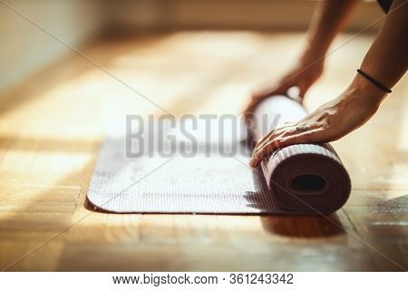Close Up Of A Womans Hands Is Rolling Up Exercise Mat And Preparing To Doing Yoga. She Is Exercising