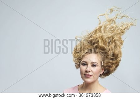 Portrait Of Positive Calm Caucasian Woman With Lifted Hair. Posing In Pink Blouse Against Gray.