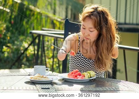 Beautiful Asian Woman Eating Breakfast At Tropical Resort.she Is Drinks Cup Of Tea Or Coffee