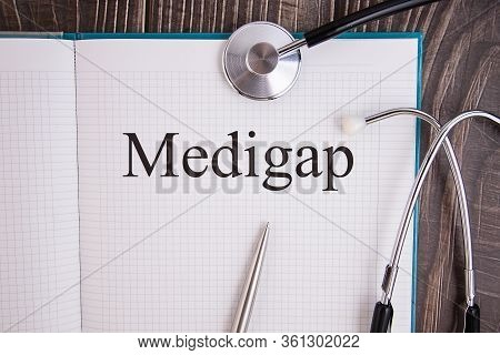 Notebook Page With Text Medigap, On A Table With A Stethoscope And Pen, Medical Concept.