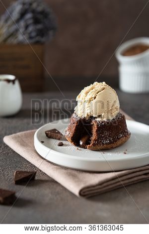 Warm Chocolate Lava Cake With Bite Taken Out Of Molten Center And Scoop Of Vanilla Ice Cream On Dark