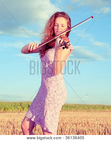 Rødhåret kvinde spille Violin udendørs på feltet. Split Toning.
