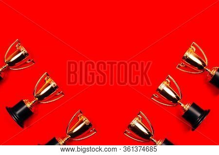 Winner Cups On A Red Background With Copy Space. Flat Lay Style.