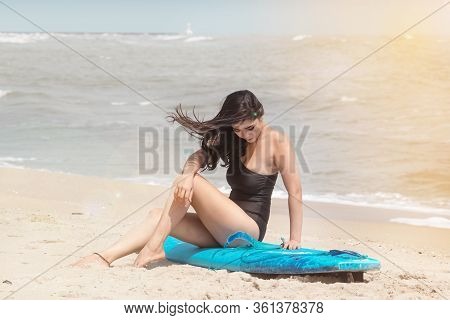 The Beautiful Woman Wearing Black Swimming Suit Sitting On  Serf Board