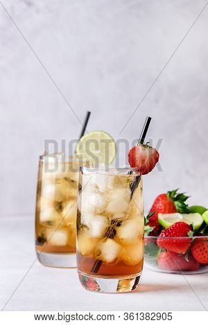 Glasses Of Cold Citrus And Strawberry Ice Tea On Light Gray Background Decorated With Ripe Lime And 