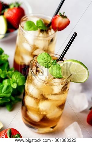 Glasses Of Cold Citrus And Strawberry Ice Tea On Light Gray Background Decorated With Ripe Lime And 