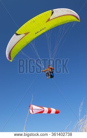 Kyiv Oblast / Ukraine - April 12, 2020: Lime Green Paraglide Is Flying Over The Wind Cone (airsock).