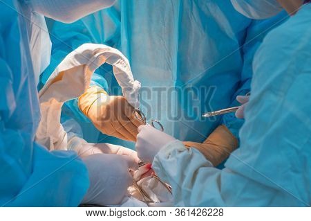 Close-up, The Hands Of Pediatric Surgeons And An Assistant Operating A Small Patient With Behind-the