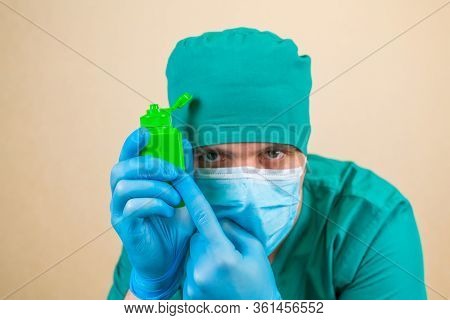 Green Antiseptic Bottle In Doctor Hands In Green Suit And Blue Mask Gloves With On Yellow Background